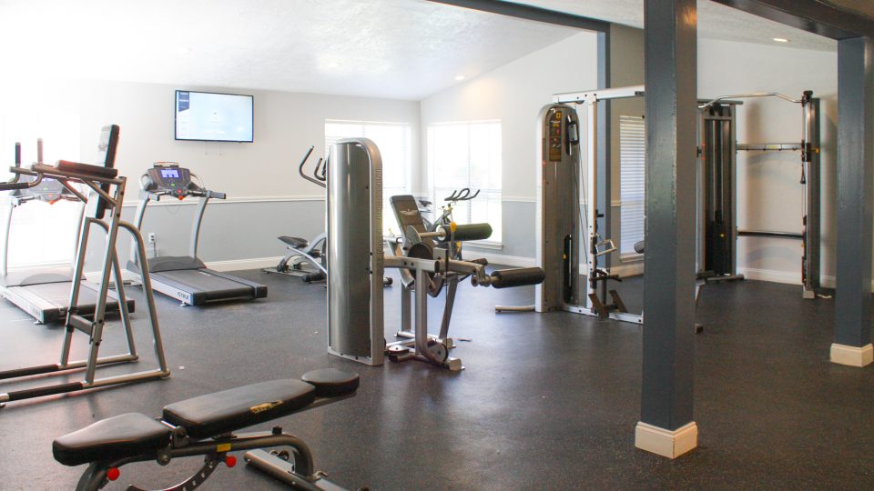 a gym room with treadmills and exercise equipment at The Caldera Apartments