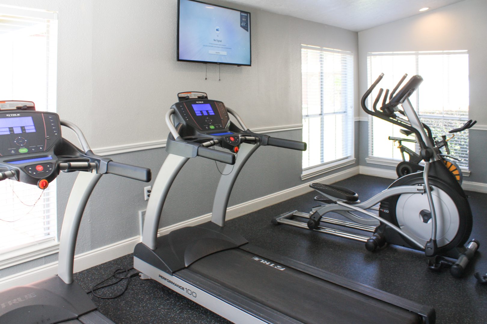 a gym room with tread machines and a flat screen tv at The Caldera Apartments